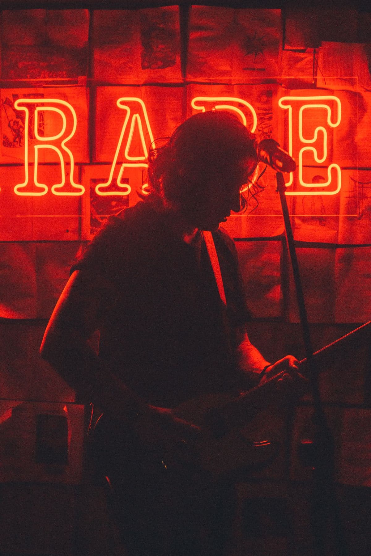 Silhouette d'un chanteur devant une enseigne au néon rouge